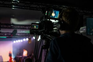 Man presenting in a modern broadcast studio and event space rental in St. Louis with a large screen display.