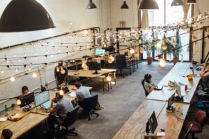 People collaborating at coworking space in St. Louis with computer monitors in the background.