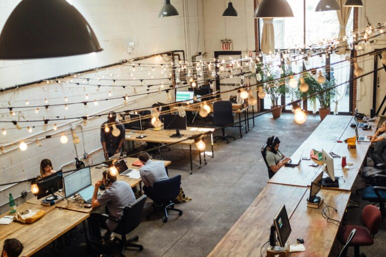 People collaborating at coworking space in St. Louis with computer monitors in the background.