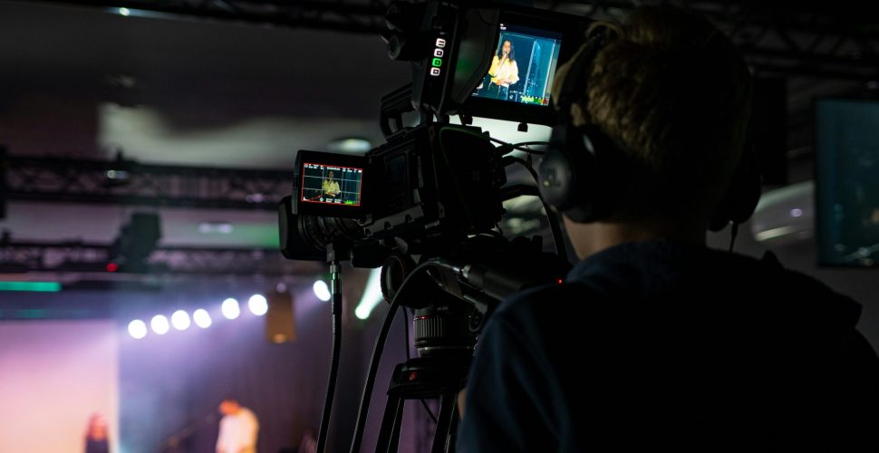 Man presenting in a modern broadcast studio and event space rental in St. Louis with a large screen display.