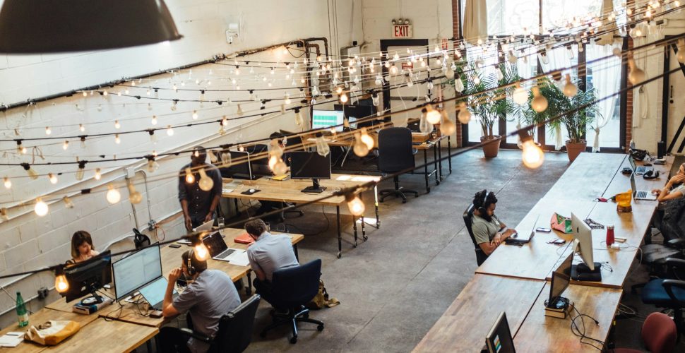 People collaborating at coworking space in St. Louis with computer monitors in the background.